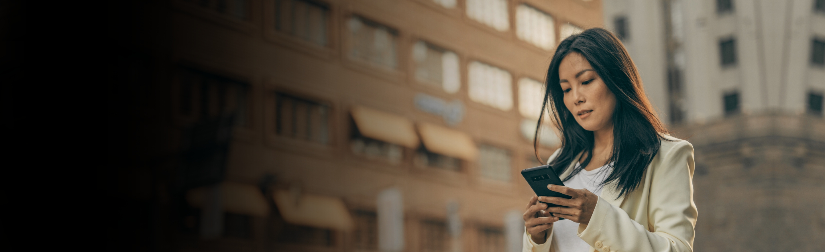 Woman checking phone in a city street wearing a yellow jacket